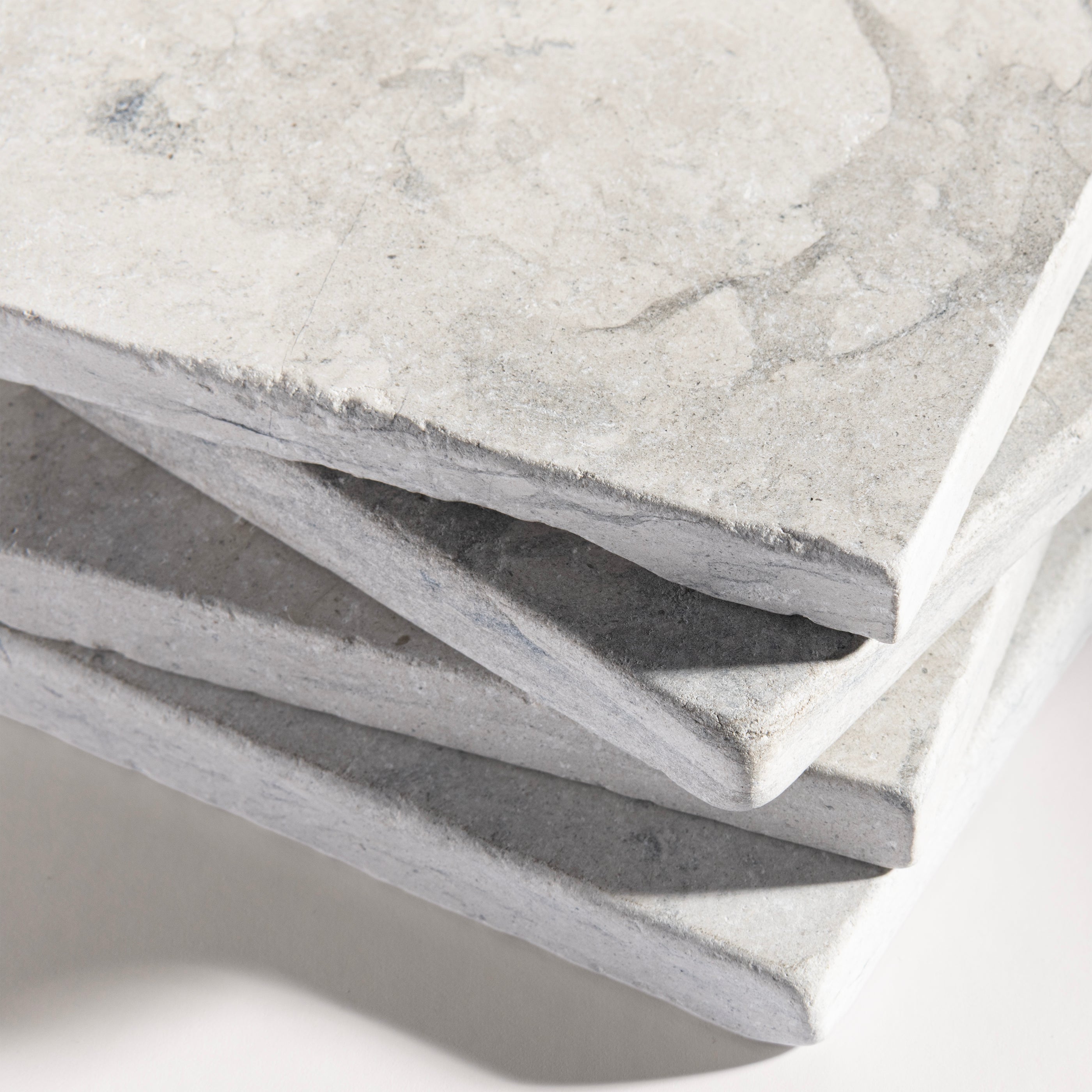 close up angle of tiles with a grey limestone pattern on a white background