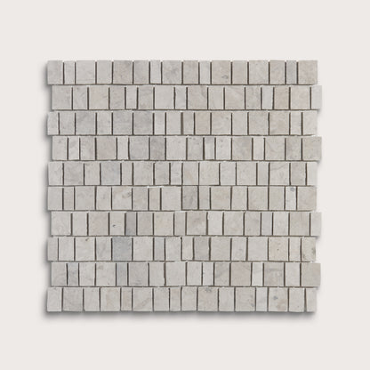 A square sample of light gray marble mosaic tiles arranged in a staggered brick pattern, shown against a solid off-white background.