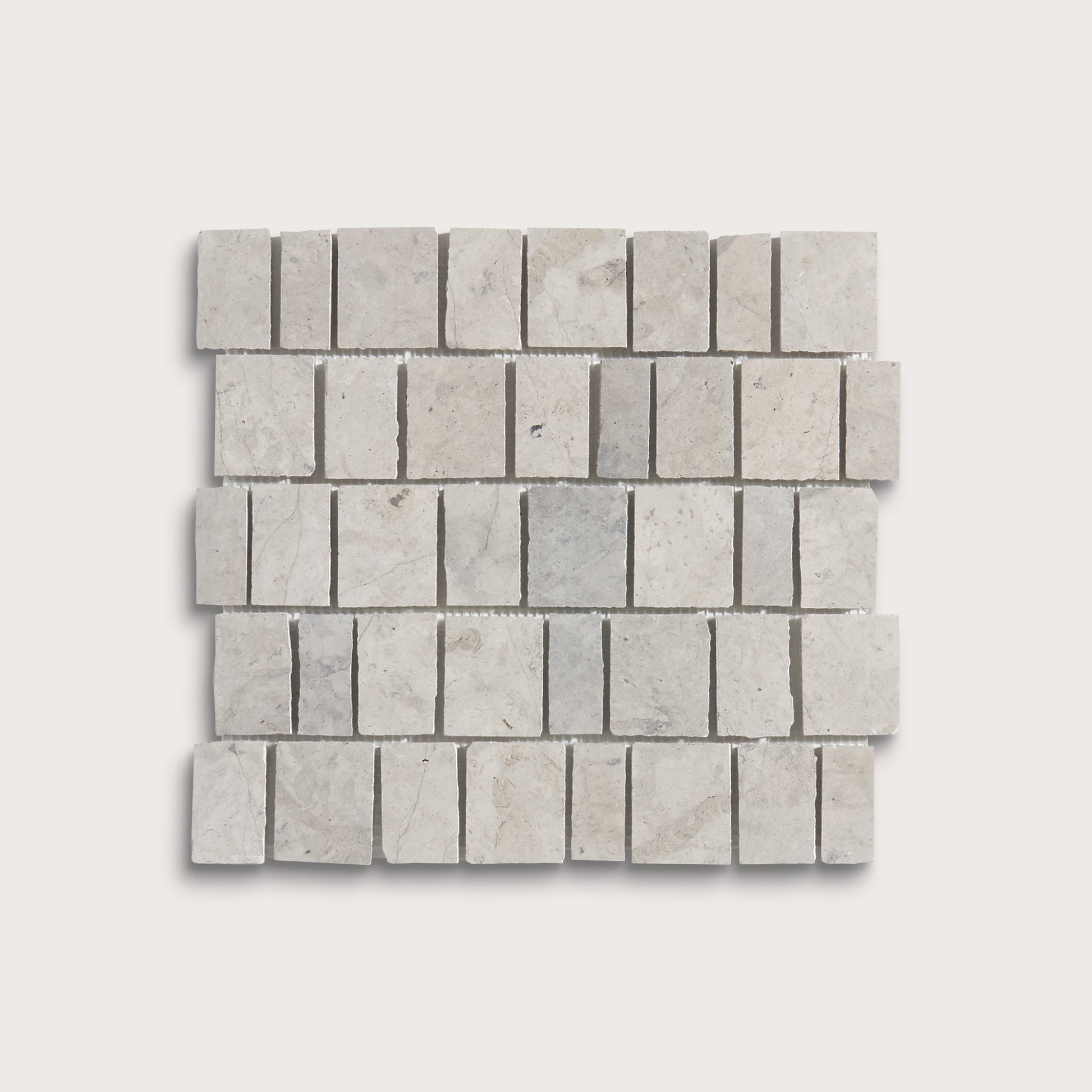A square mosaic tile sample made of light gray rectangular travertine or marble chips arranged in a staggered brick pattern, shown on a plain light gray background.