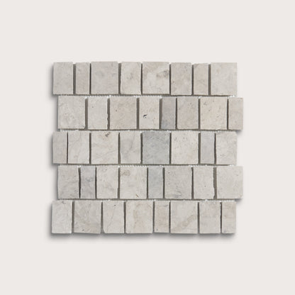 A square mosaic tile sample made of light gray rectangular travertine or marble chips arranged in a staggered brick pattern, shown on a plain light gray background.