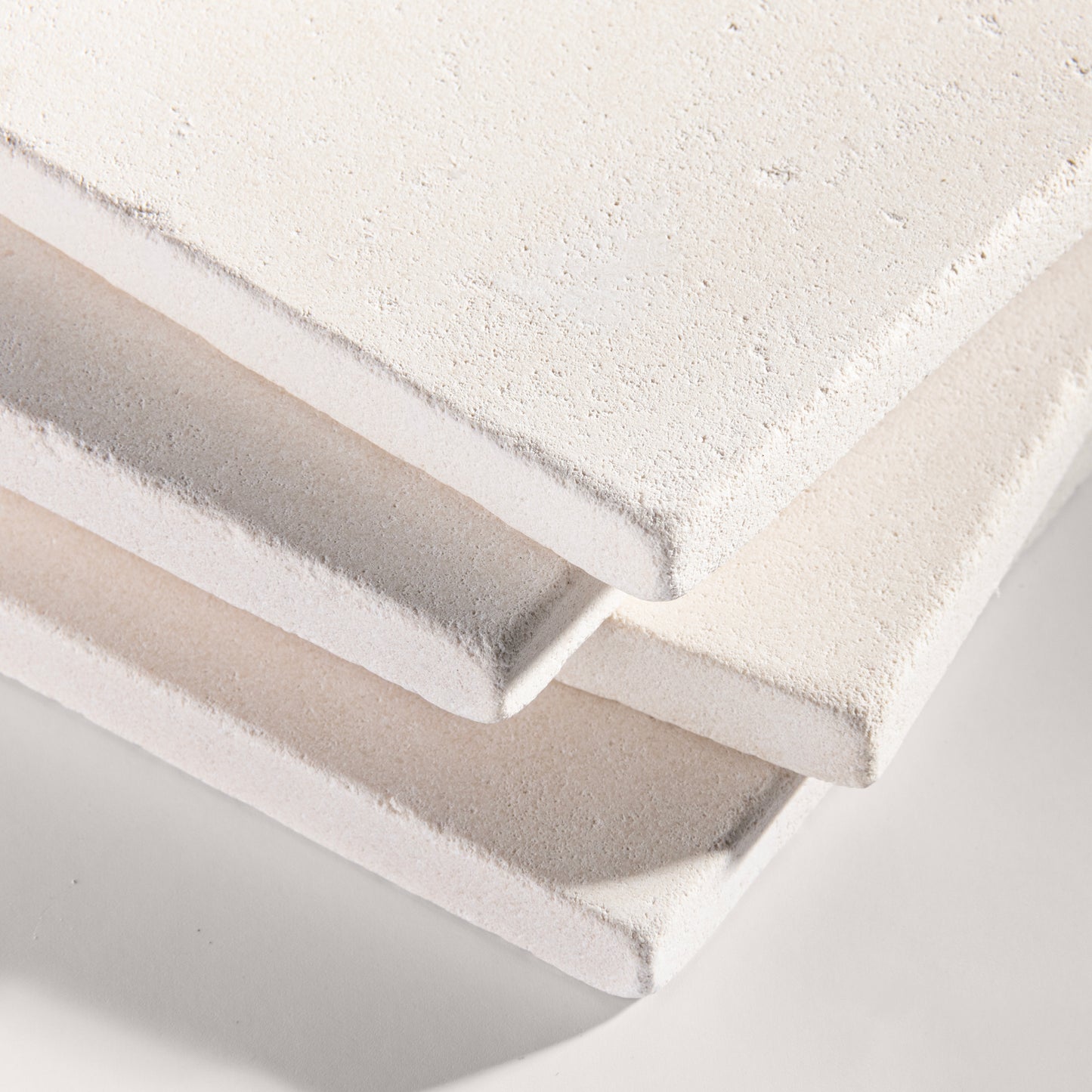 close up angle of tiles with a white limestone pattern on a white background