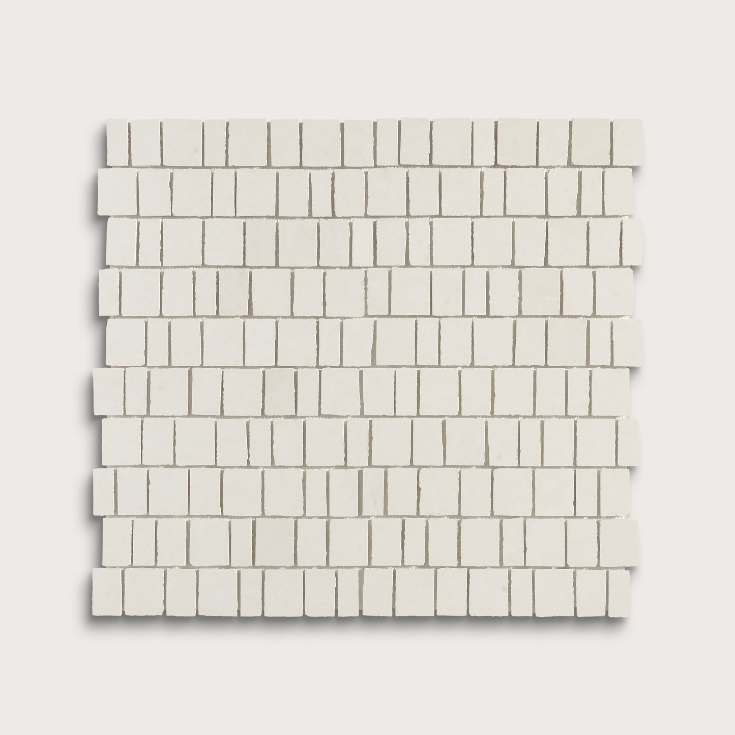 A square sample of small rectangular off-white mosaic tiles arranged in staggered rows, shown on a light warm gray background.