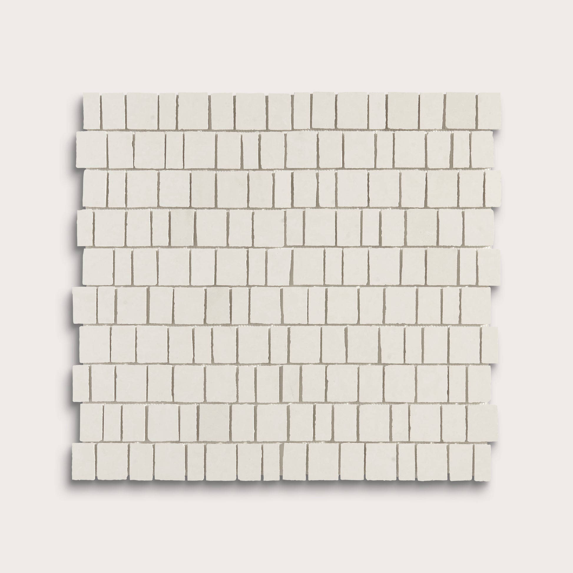 A square sample of small rectangular off-white mosaic tiles arranged in staggered rows, shown on a light warm gray background.