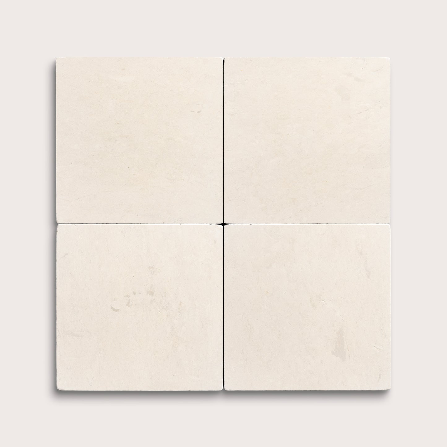 four square tiles with a beige limestone pattern on a white background