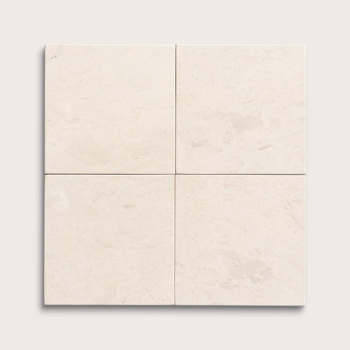 four square tiles with a beige limestone pattern on a white background