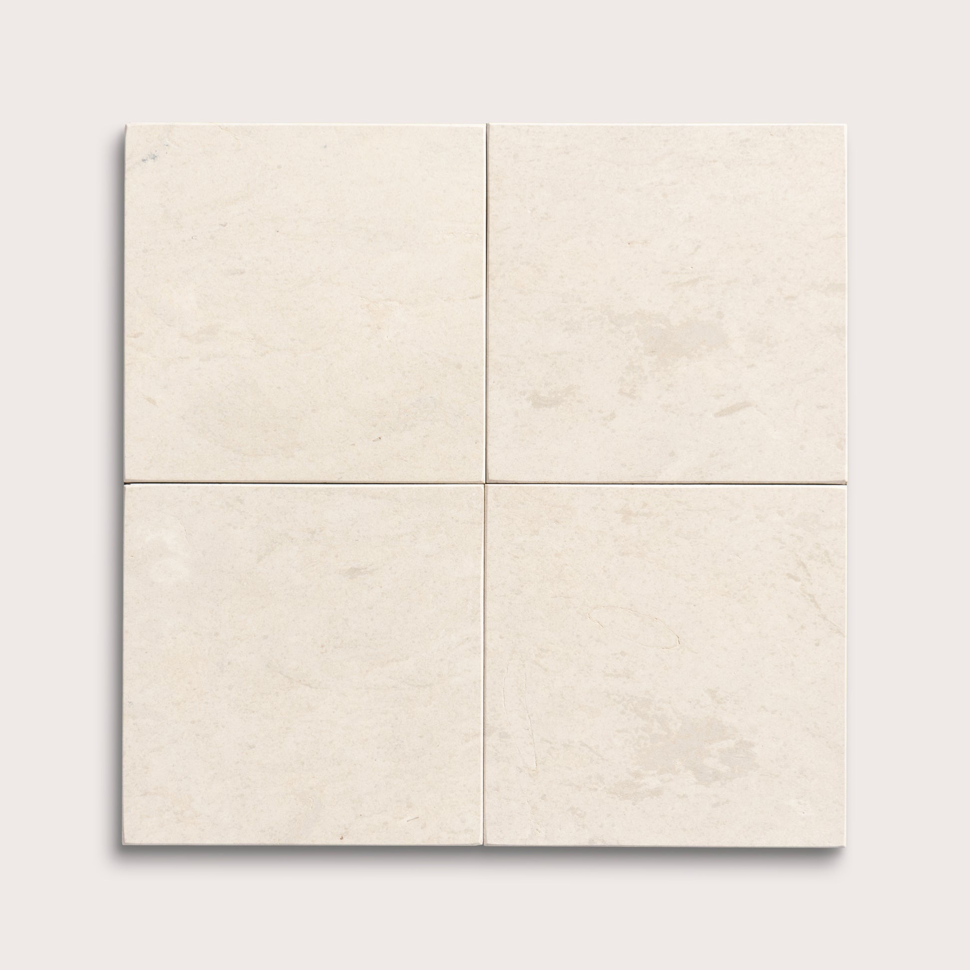 four square tiles with a beige limestone pattern on a white background