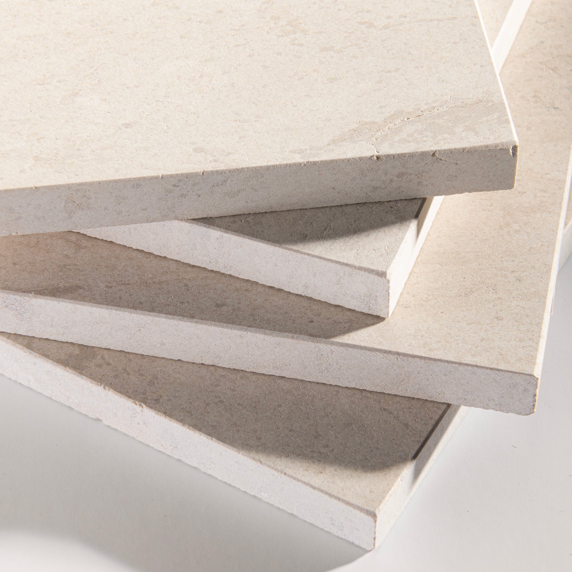 close up angle of tiles with a beige limestone pattern on a white background