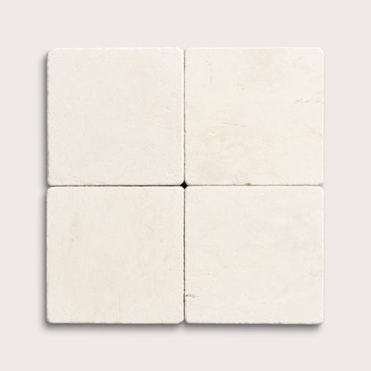 four square tiles with a beige limestone pattern on a white background
