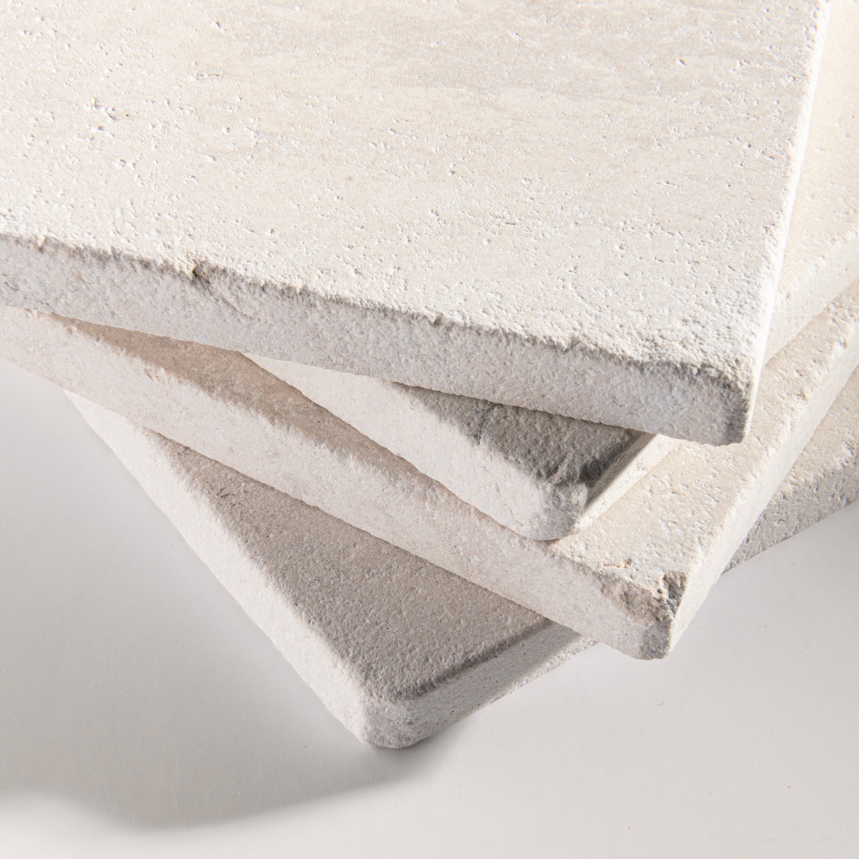 close up angle of tiles with a beige limestone pattern on a white background