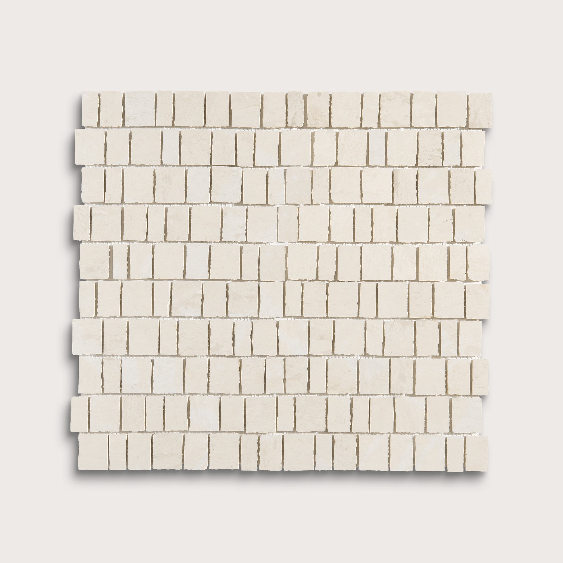 A square mosaic tile sample made of small rectangular off-white stone pieces arranged in staggered rows, shown on a light neutral background.