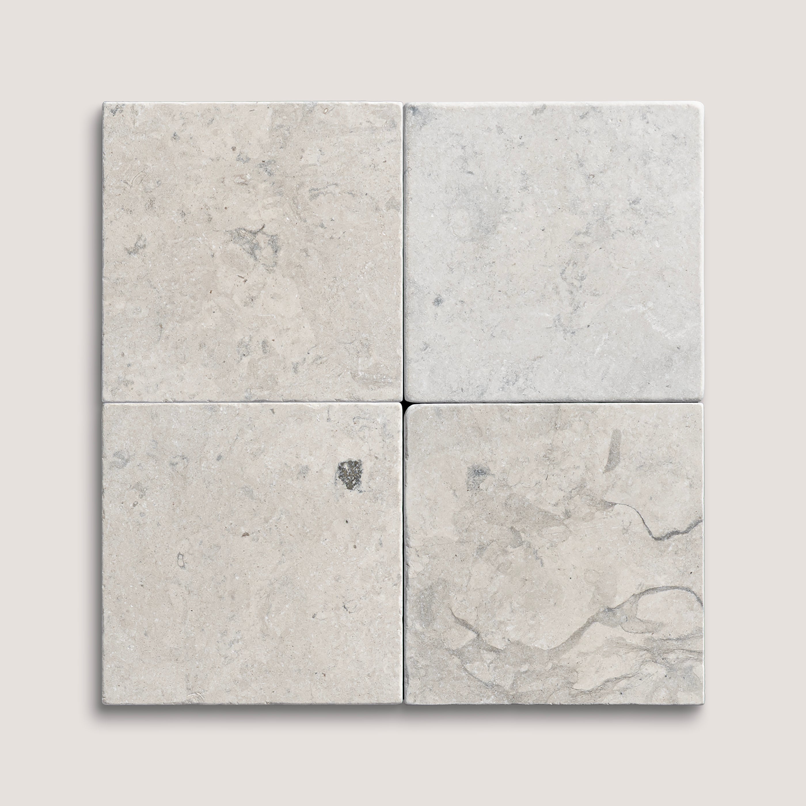 Four gray limestone tiles arranged in a grid pattern on a light gray background