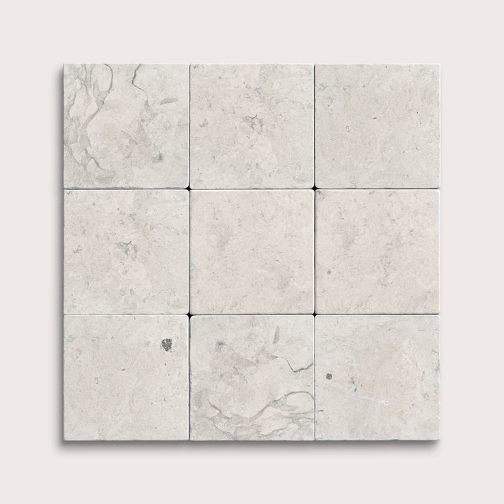 Nine square limestone tiles with a light gray marble pattern on a white background