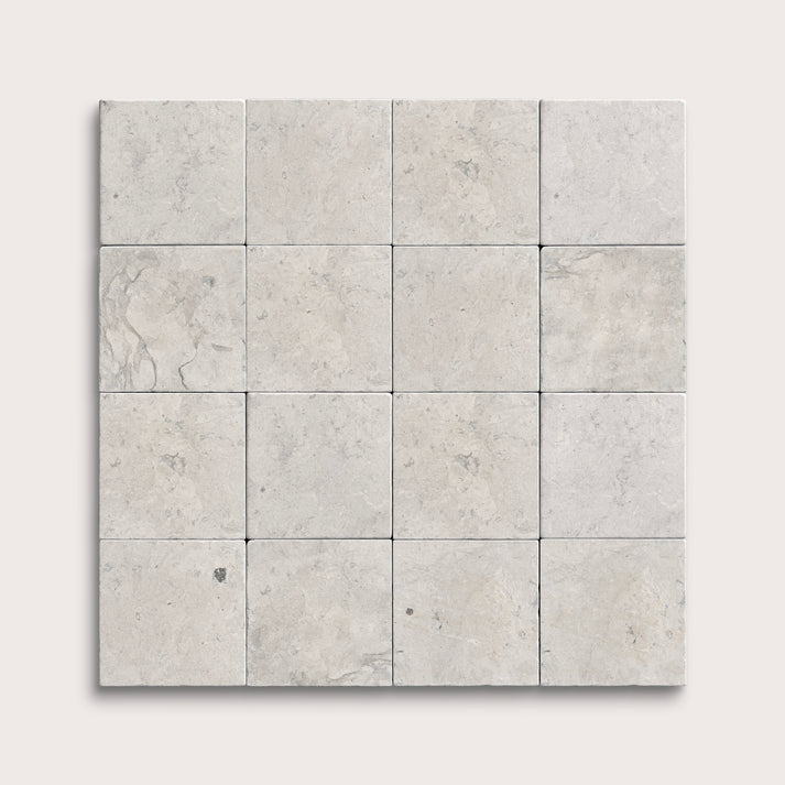 Square limestone tiles with a gray, textured pattern on a white background