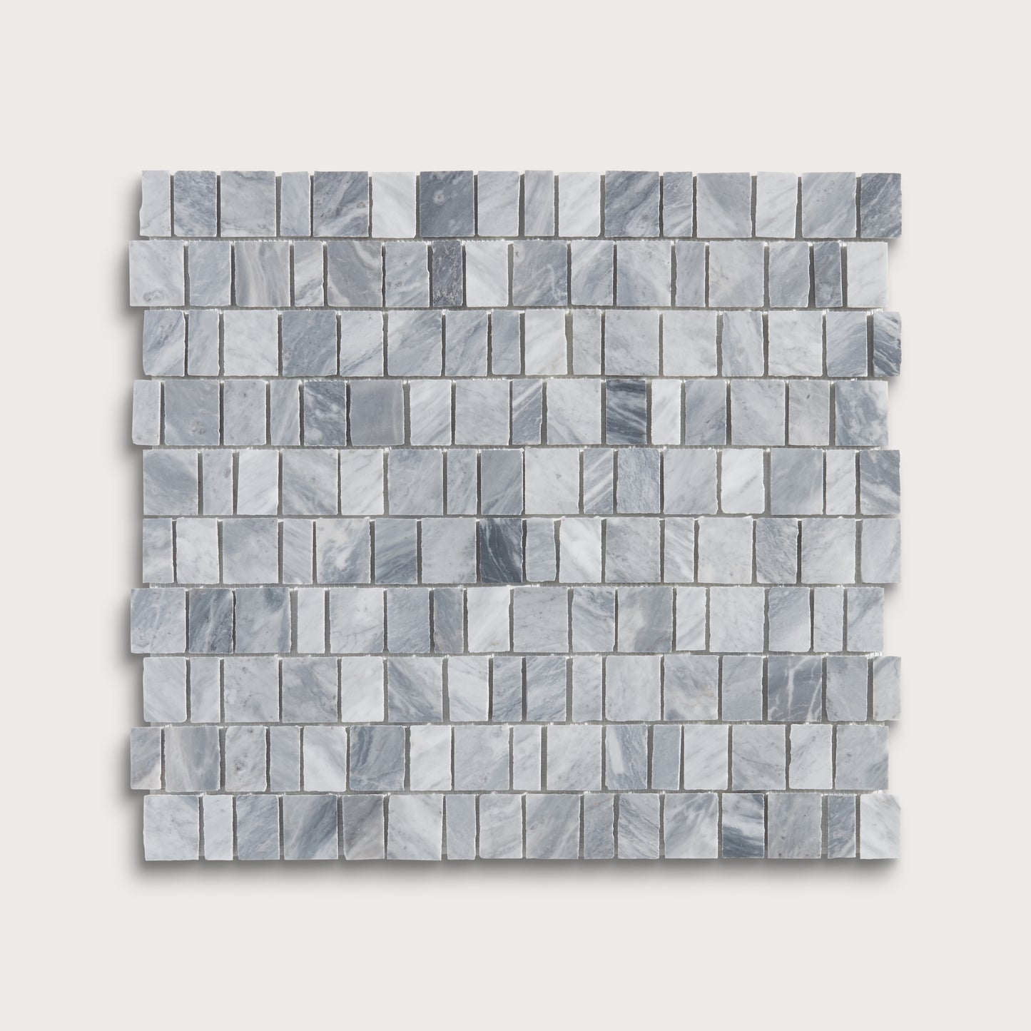 A square sample of small rectangular marble mosaic tiles in light gray and white with subtle darker gray veining, shown on a plain light beige background.