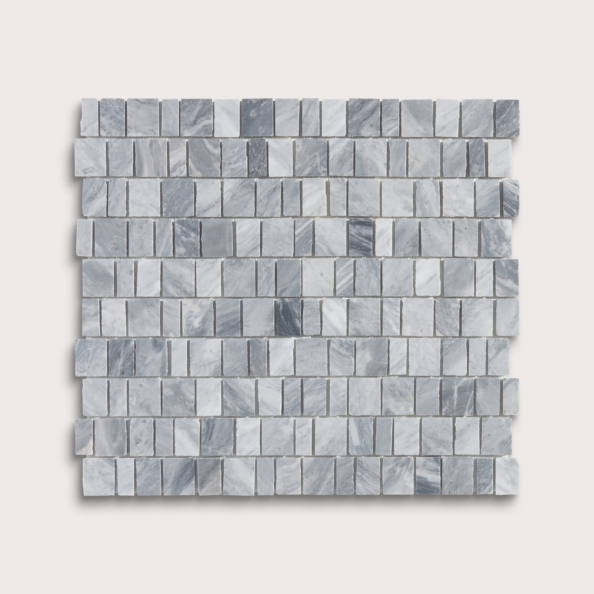A square sample of small rectangular marble mosaic tiles in light gray and white with subtle darker gray veining, shown on a plain light beige background.