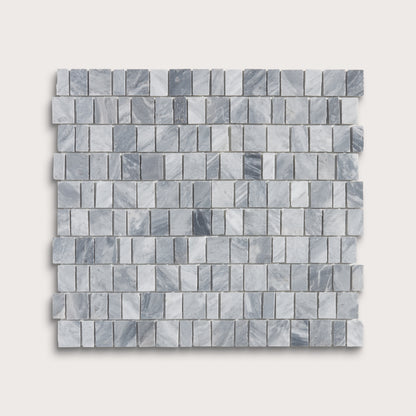 A square sample of small rectangular marble mosaic tiles in light gray and white with subtle darker gray veining, shown on a plain light beige background.