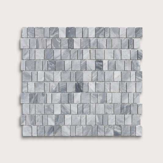 A square sample of small rectangular marble mosaic tiles in light gray and white with subtle darker gray veining, shown on a plain light beige background.