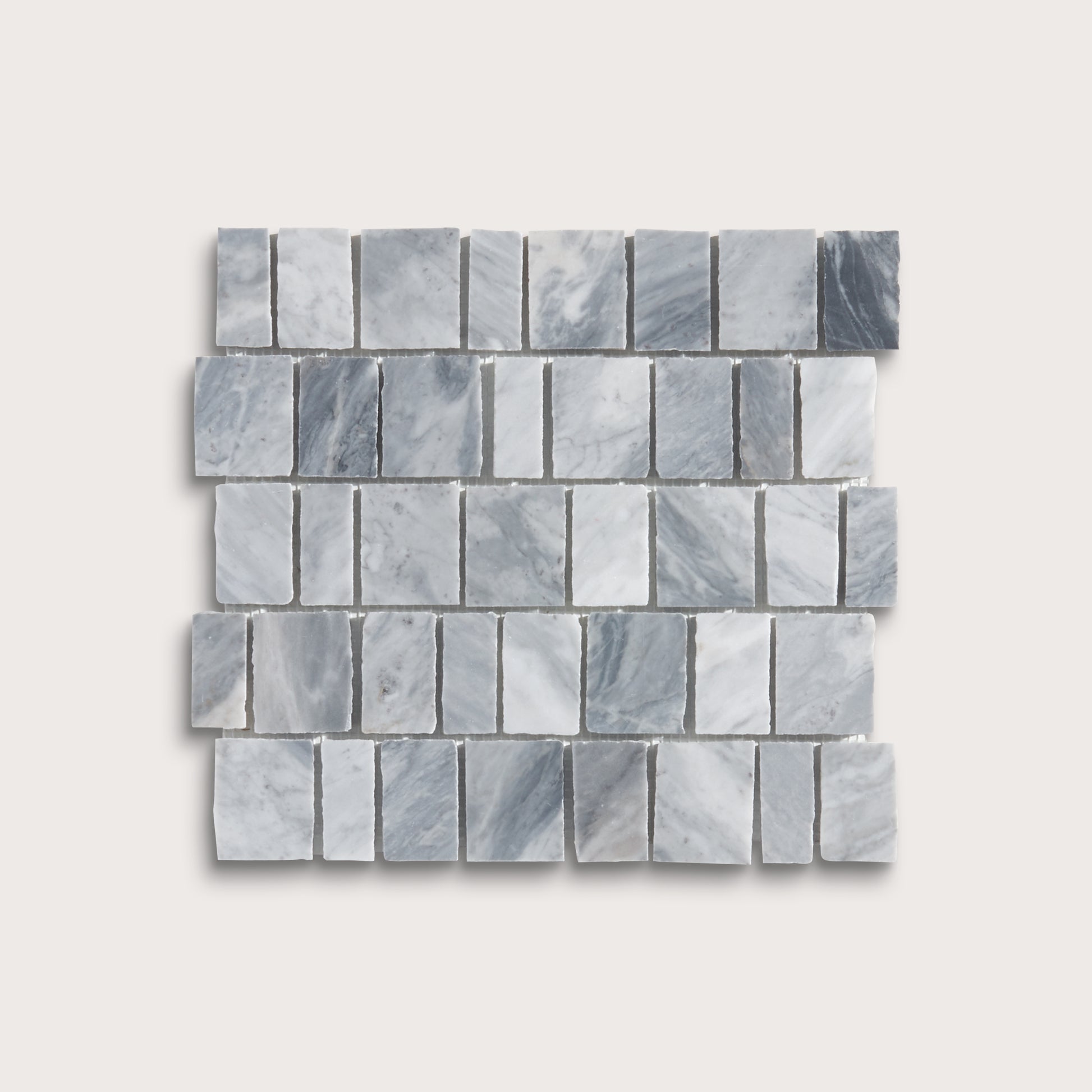 A rectangular mosaic tile sample made of small gray marble-like blocks arranged in staggered rows, shown on a light warm gray background.