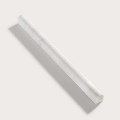 A white marble pencil trim with subtle natural veining, shown diagonally on a light beige background with a soft shadow.