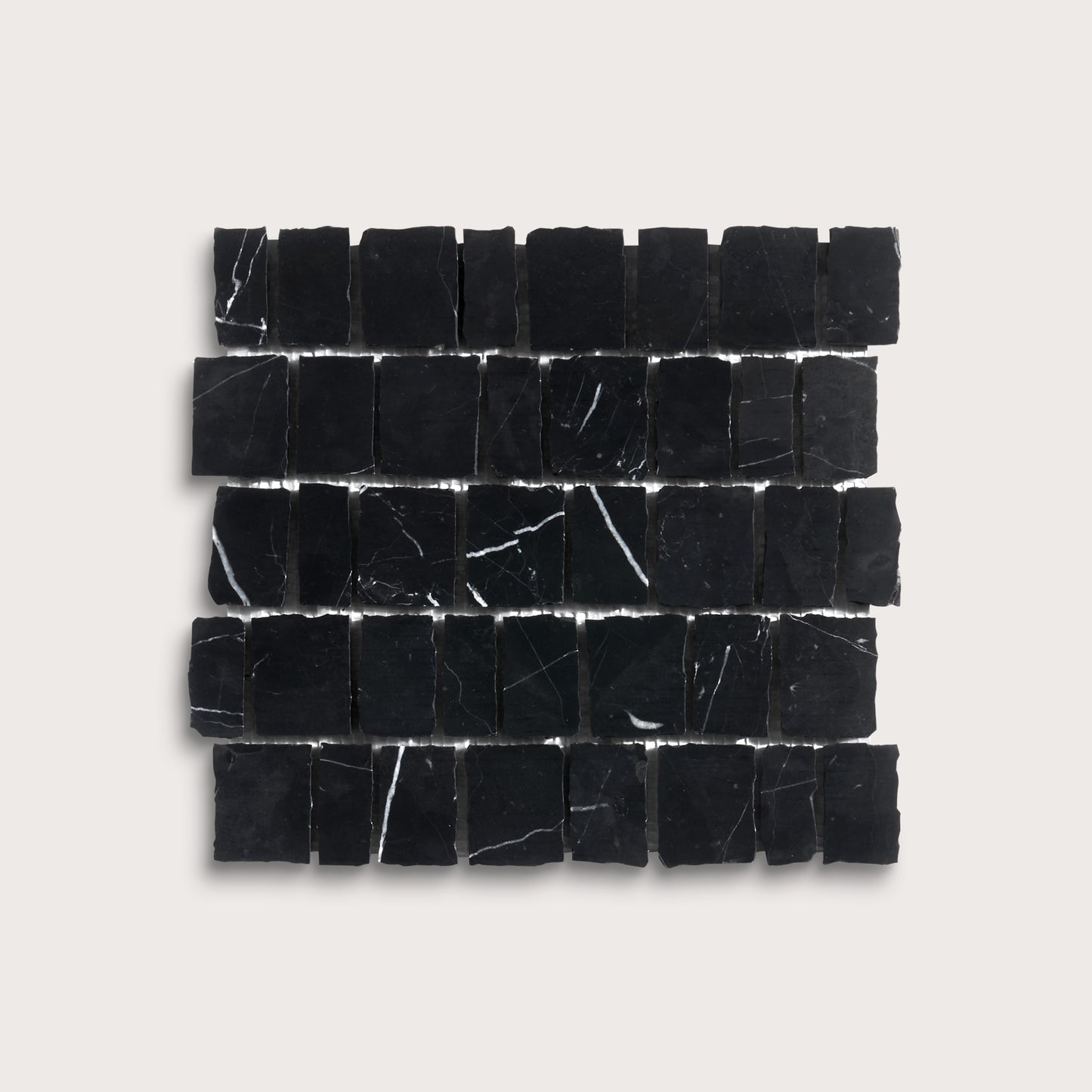 A rectangular arrangement of small black stone tiles with natural white veining, displayed on a light beige background.