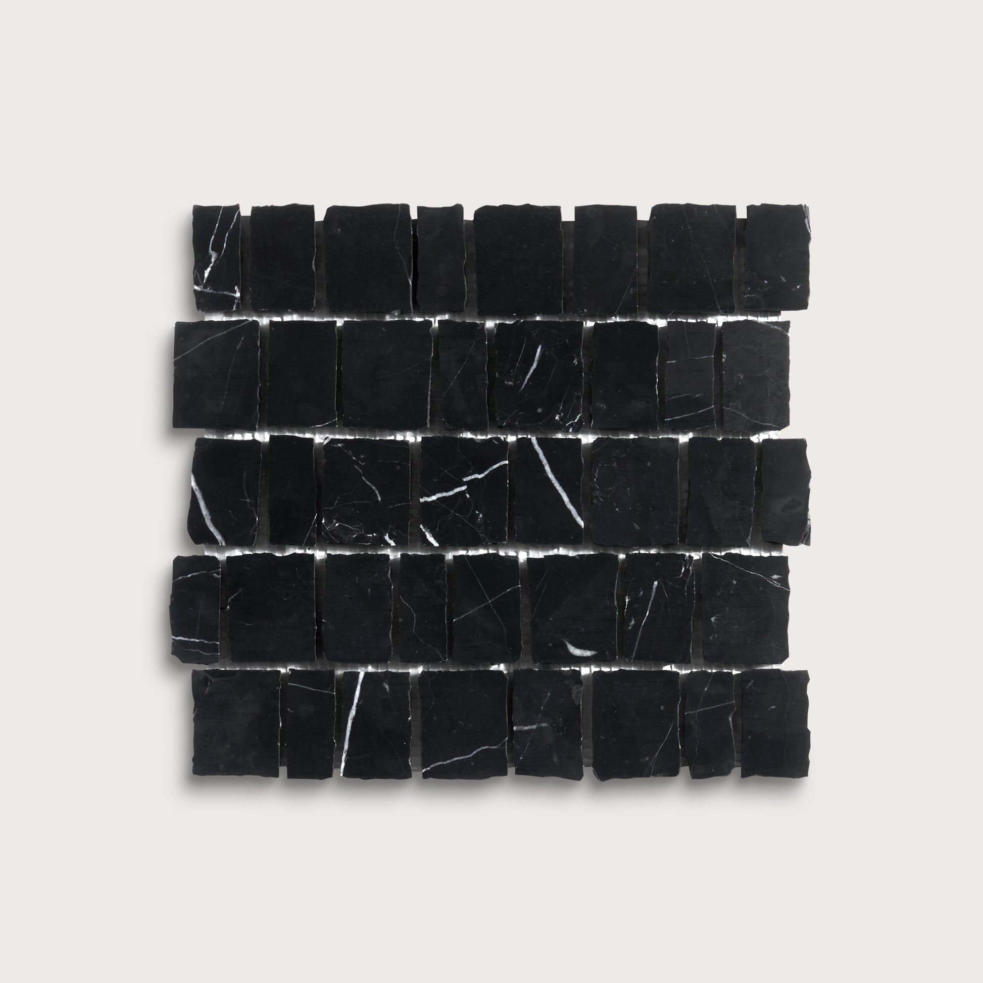 A rectangular arrangement of small black stone tiles with natural white veining, displayed on a light beige background.