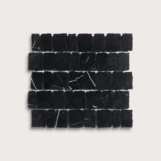 A rectangular arrangement of small black stone tiles with natural white veining, displayed on a light beige background.