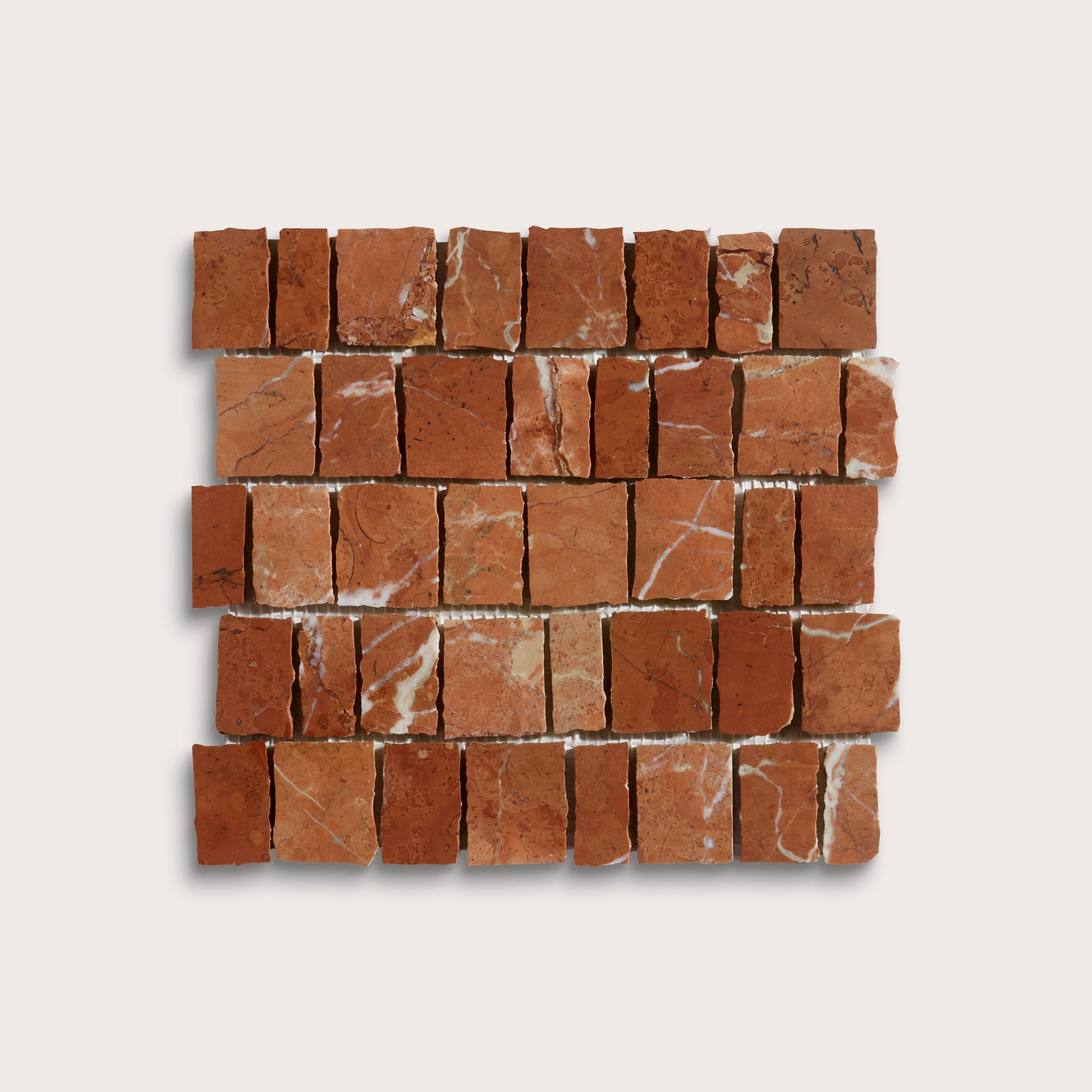 A square mosaic tile sample made of small reddish-brown stone blocks with natural white veining, arranged in a brick pattern on a light gray background.
