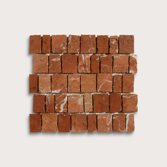 A square mosaic tile sample made of small reddish-brown stone blocks with natural white veining, arranged in a brick pattern on a light gray background.