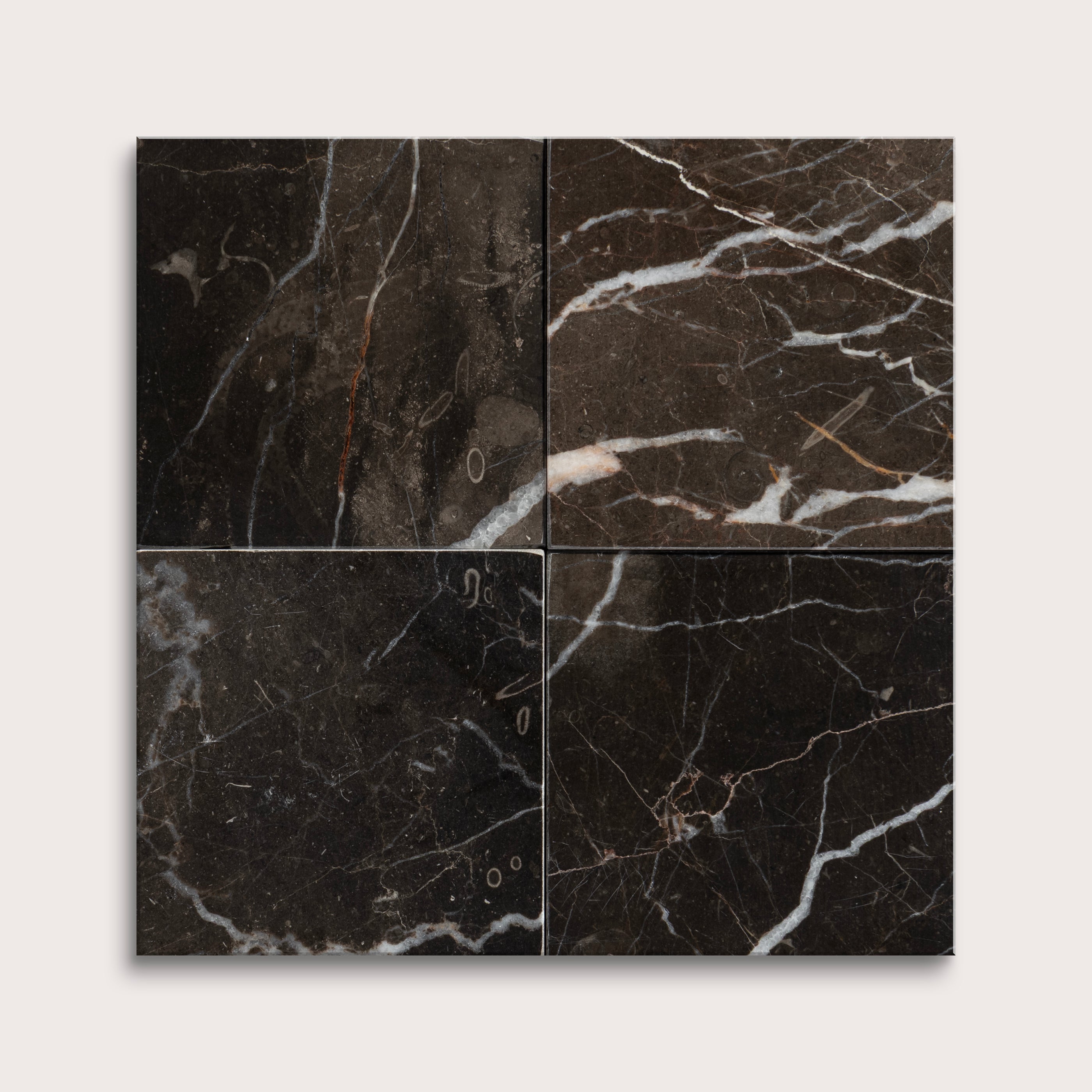 Four black marble tiles with white veins on a light gray background