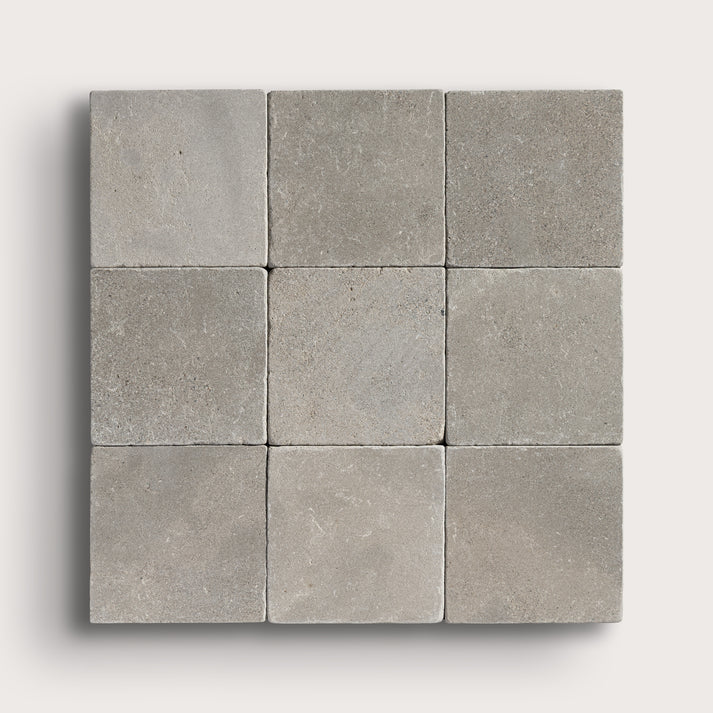 grey limestone square tile in a grid pattern on light grey background