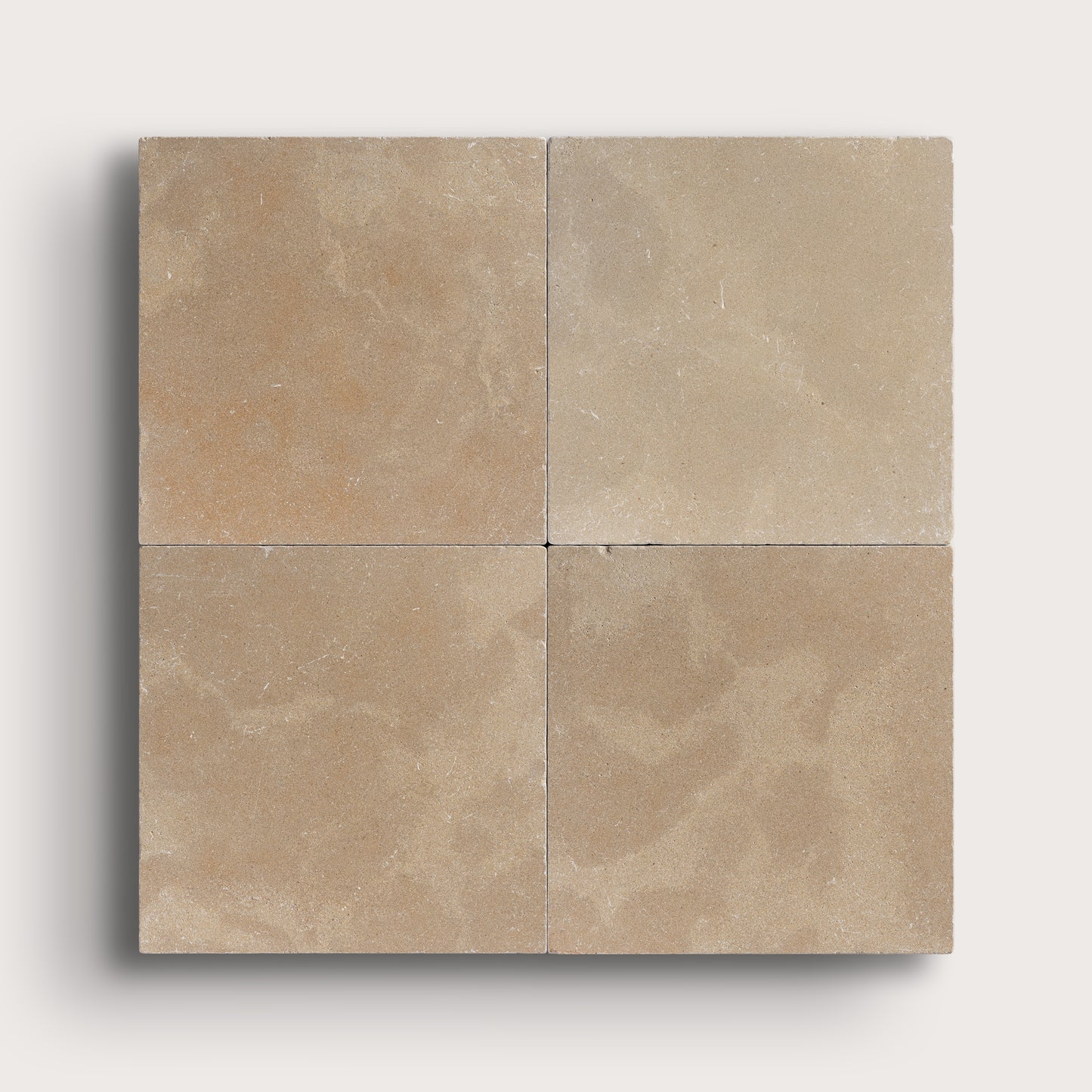 Four beige limestone tiles arranged in a grid pattern on a light gray background