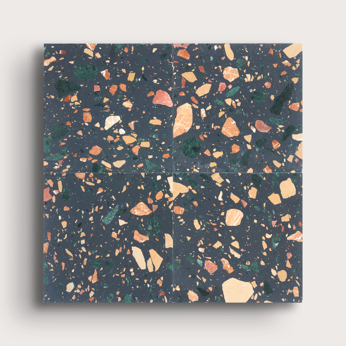 Four square terrazzo-style tiles arranged in a 2x2 grid, featuring a dark charcoal gray background with scattered peach, beige, green, and orange flecks, shown against a light gray background.
