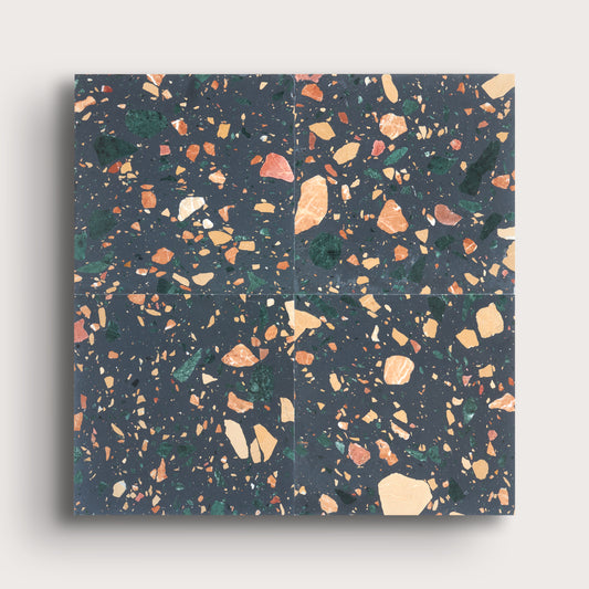Four square terrazzo-style tiles arranged in a 2x2 grid, featuring a dark charcoal gray background with scattered peach, beige, green, and orange flecks, shown against a light gray background.