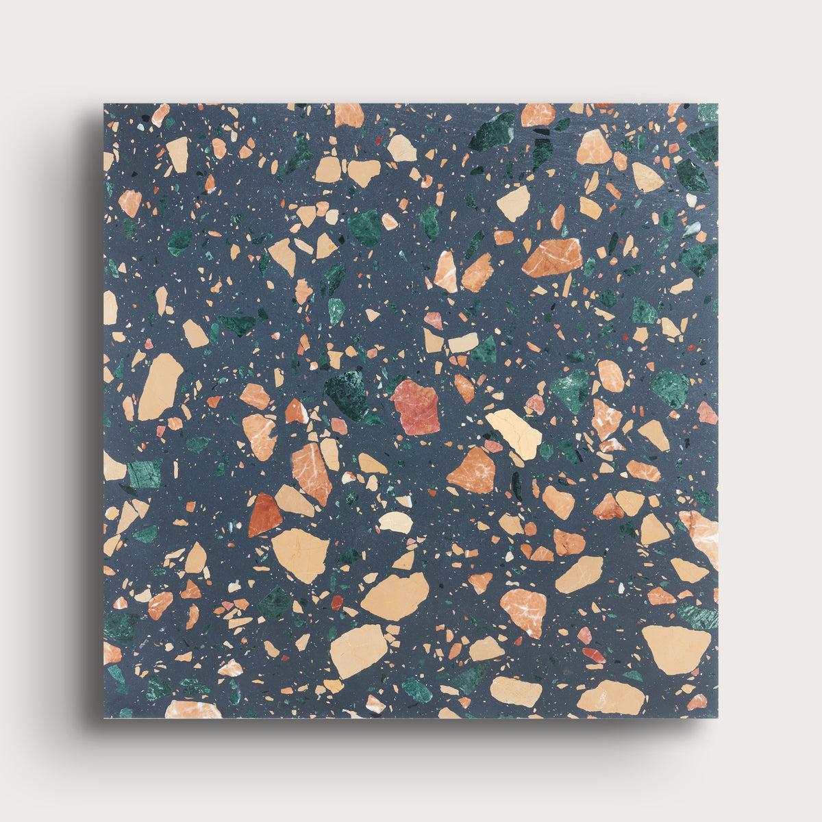 A square sample of terrazzo-style surface material with a dark blue-gray base and scattered multicolored chips in beige, orange, green, and white, shown against a light neutral background.