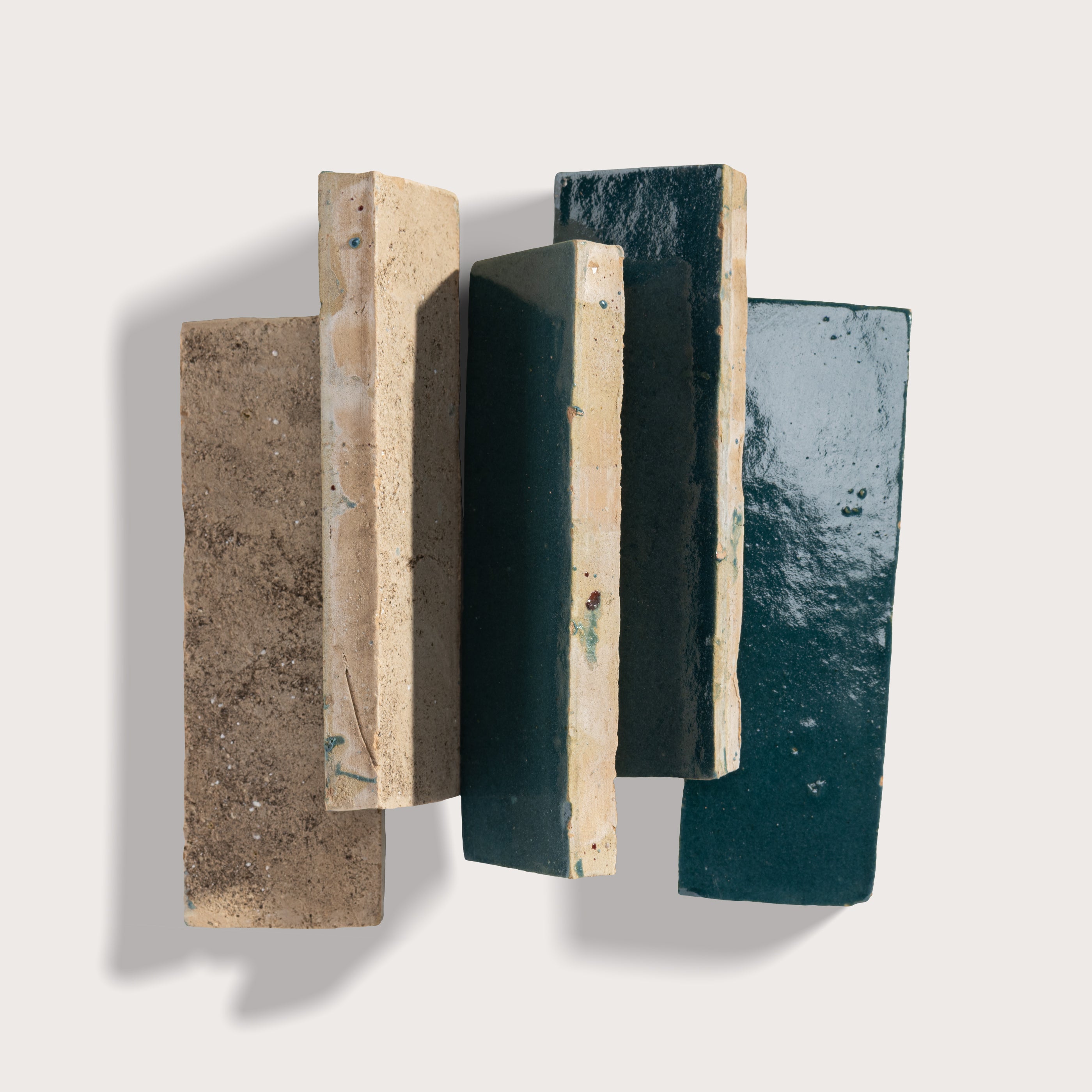 Three rectangular zellige tiles with different textures and colors on a light gray background