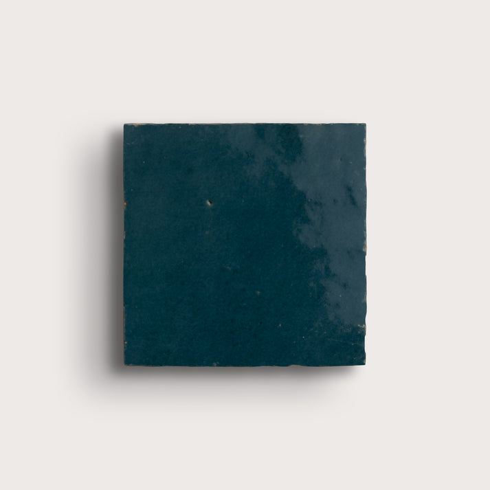 Square dark blue zellige tile on a light gray background