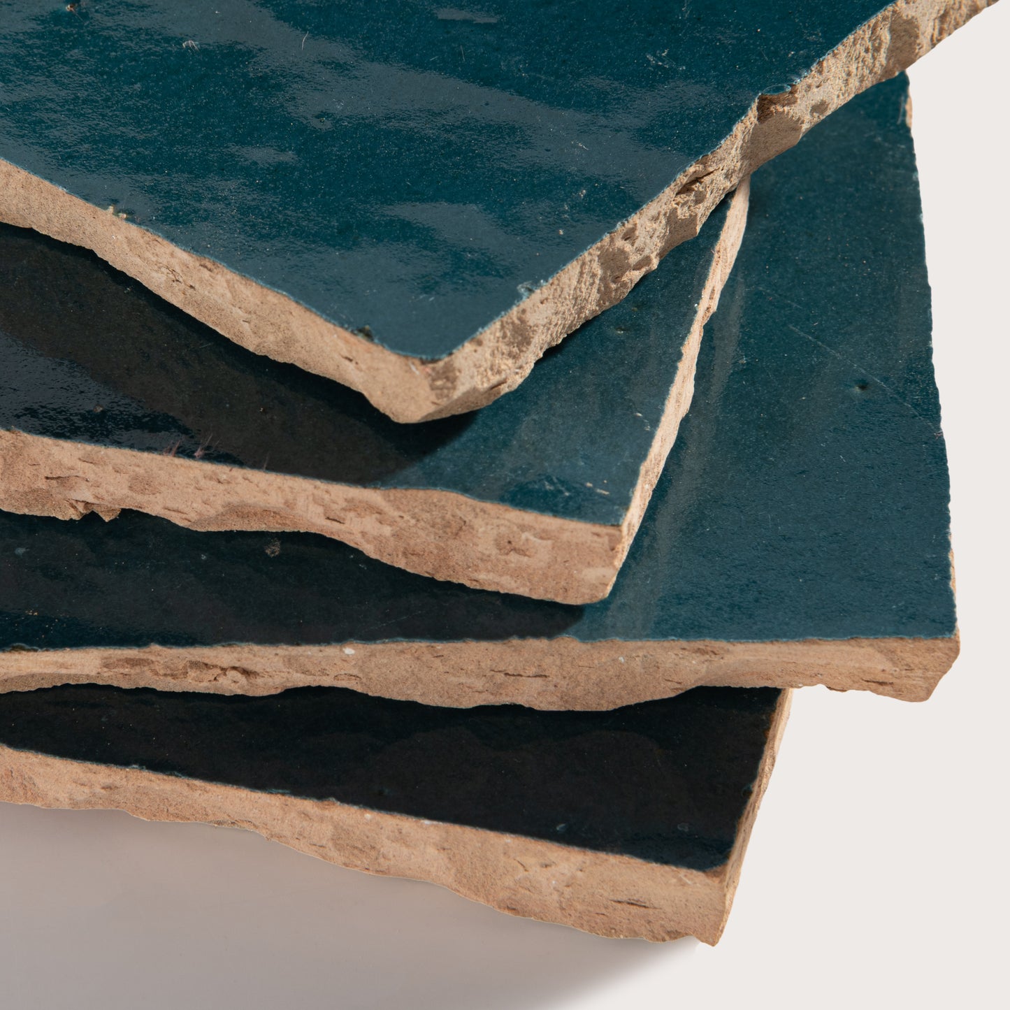 Stack of dark blue zellige tiles with a beige border on a white background