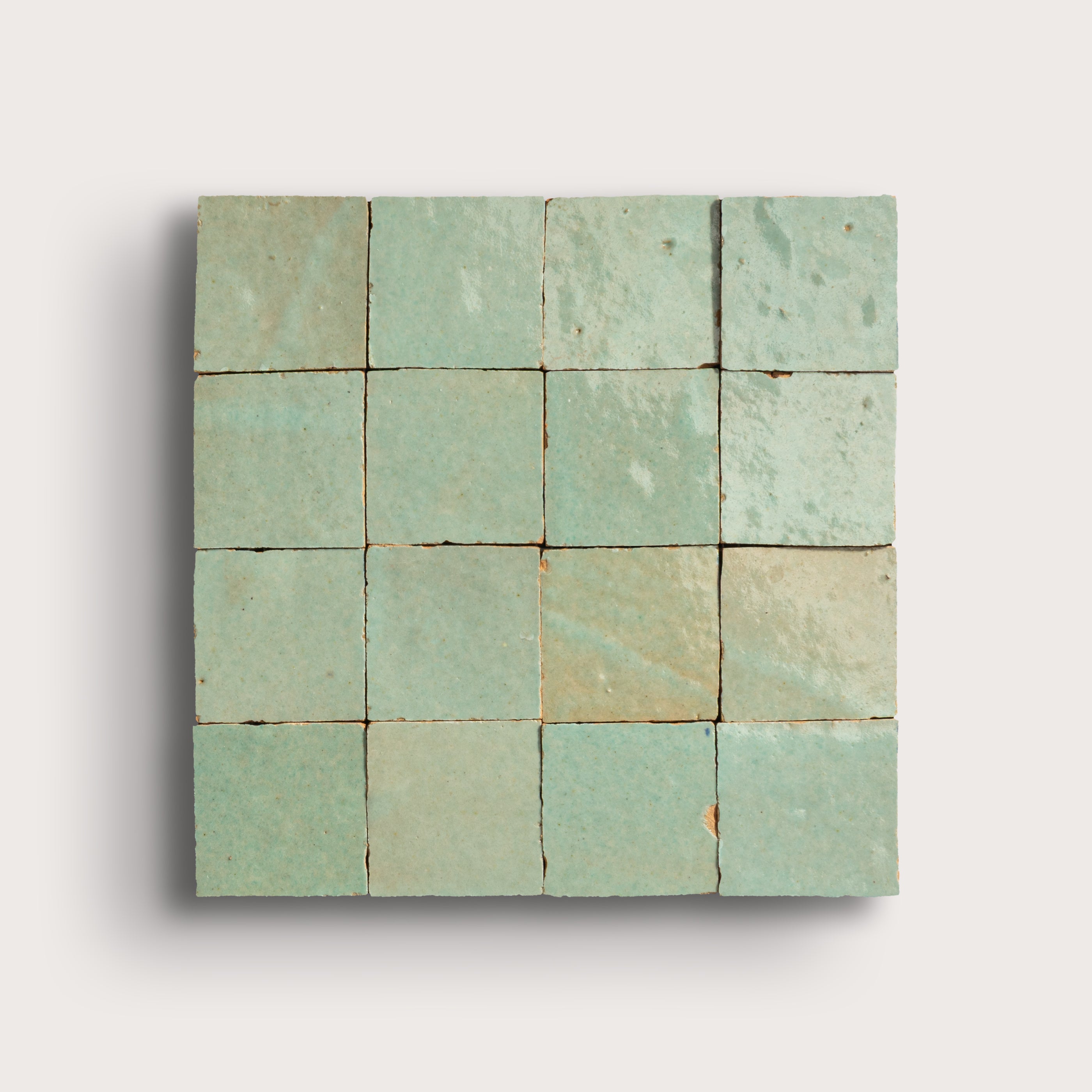 Square zellige green tile with a grid pattern on a light gray background