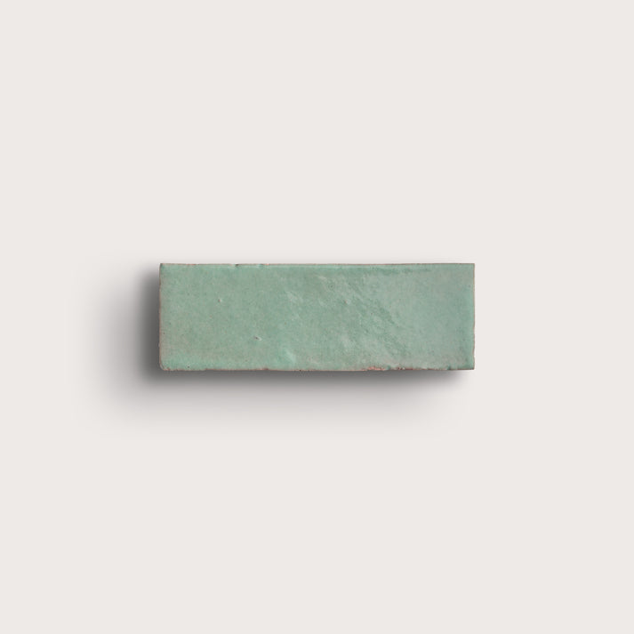 Rectangular green zellige tile on a light gray background