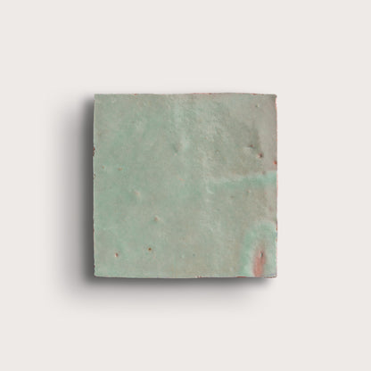 Square zellige tile with a textured green surface on a white background