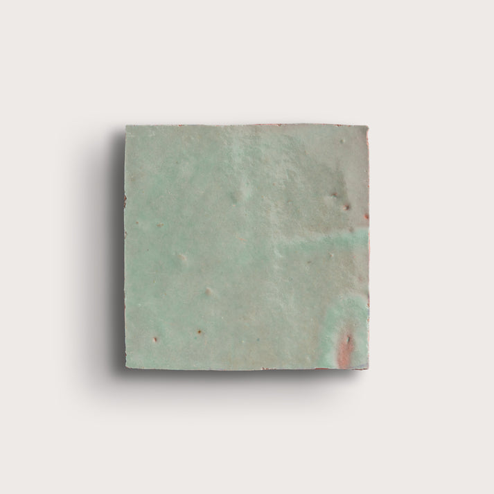 Square zellige tile with a textured green surface on a white background