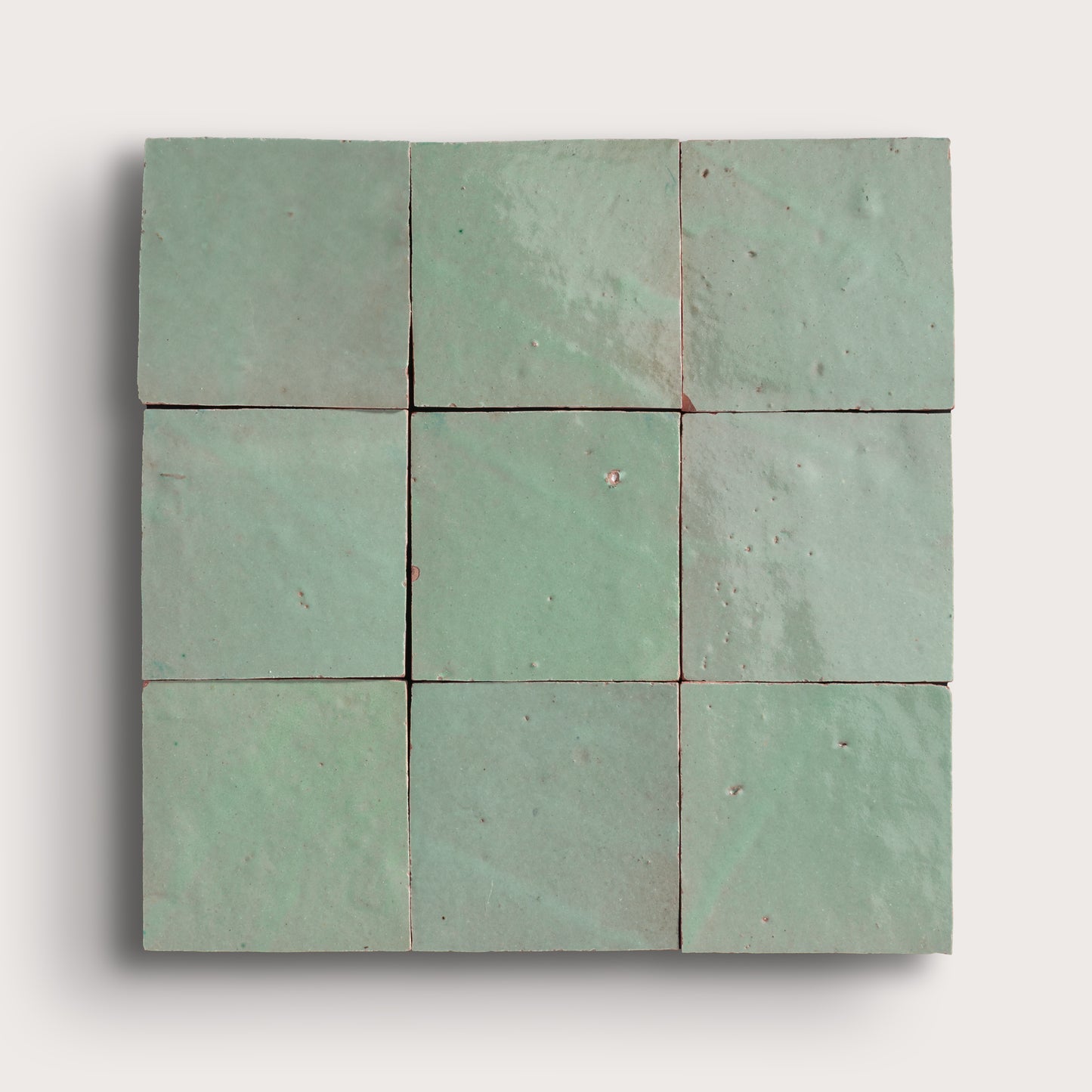 Nine square green zellige tiles arranged in a 3x3 grid on a white background