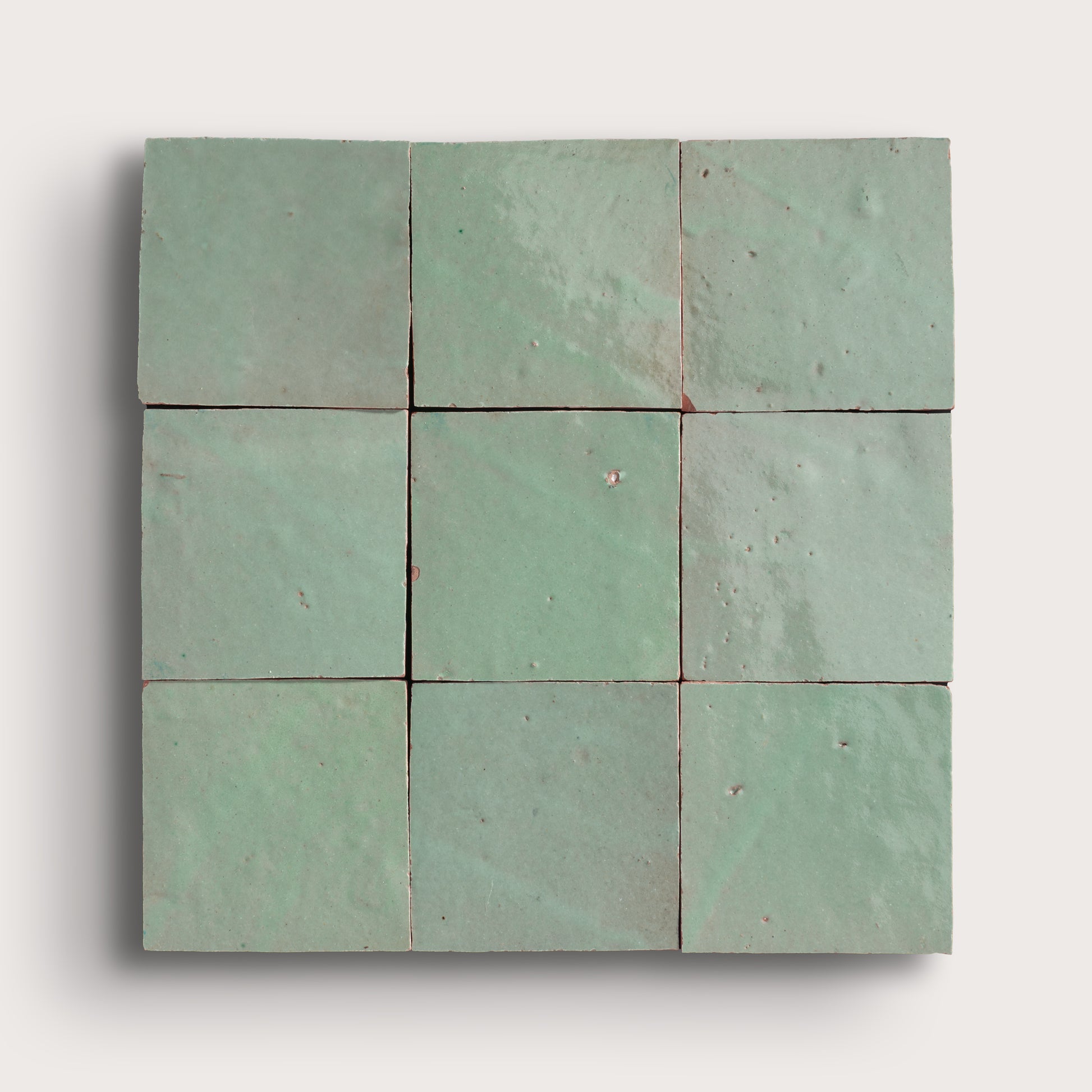 Nine square green zellige tiles arranged in a 3x3 grid on a white background