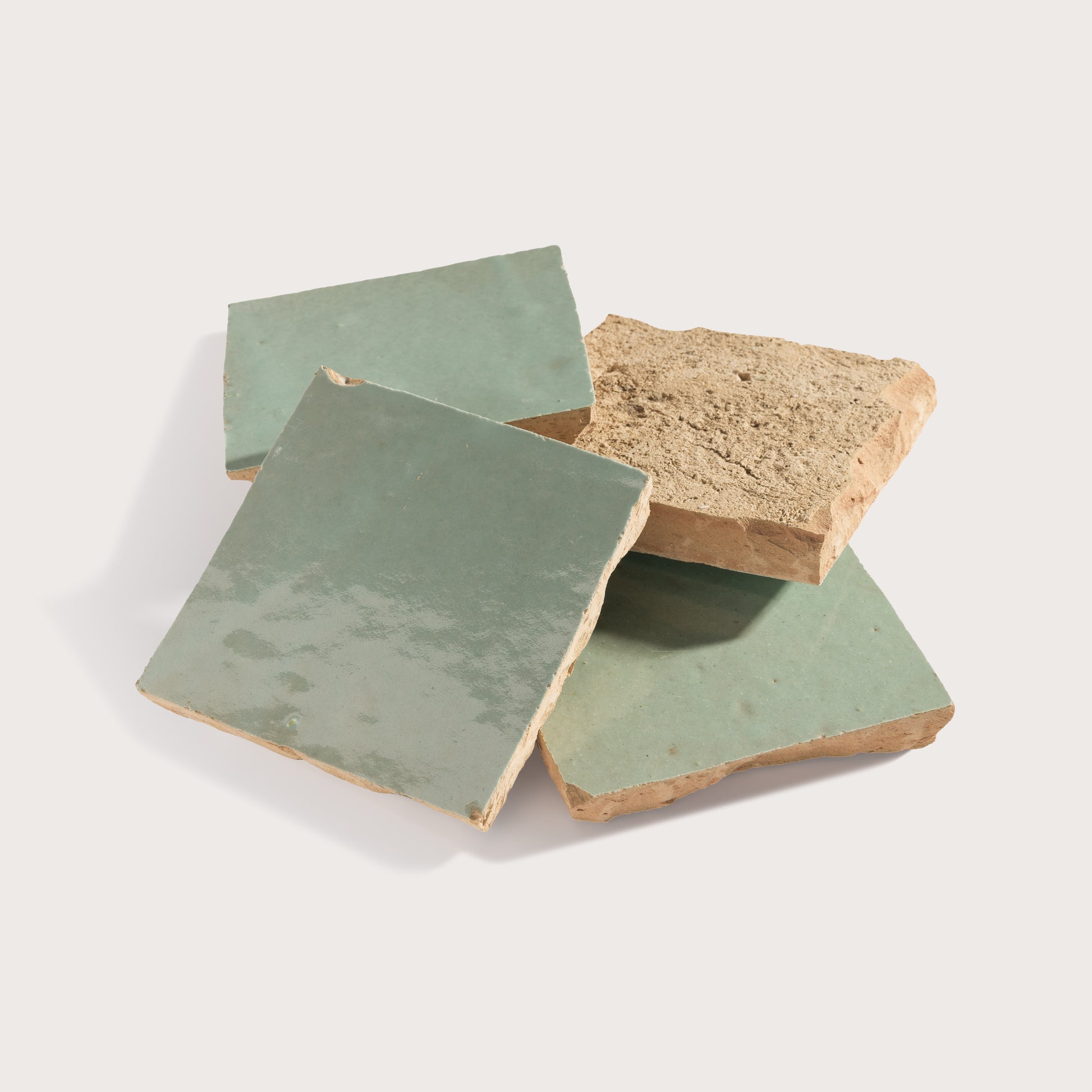 Three zellige tiles with green glaze and natural brown edges on a light gray background