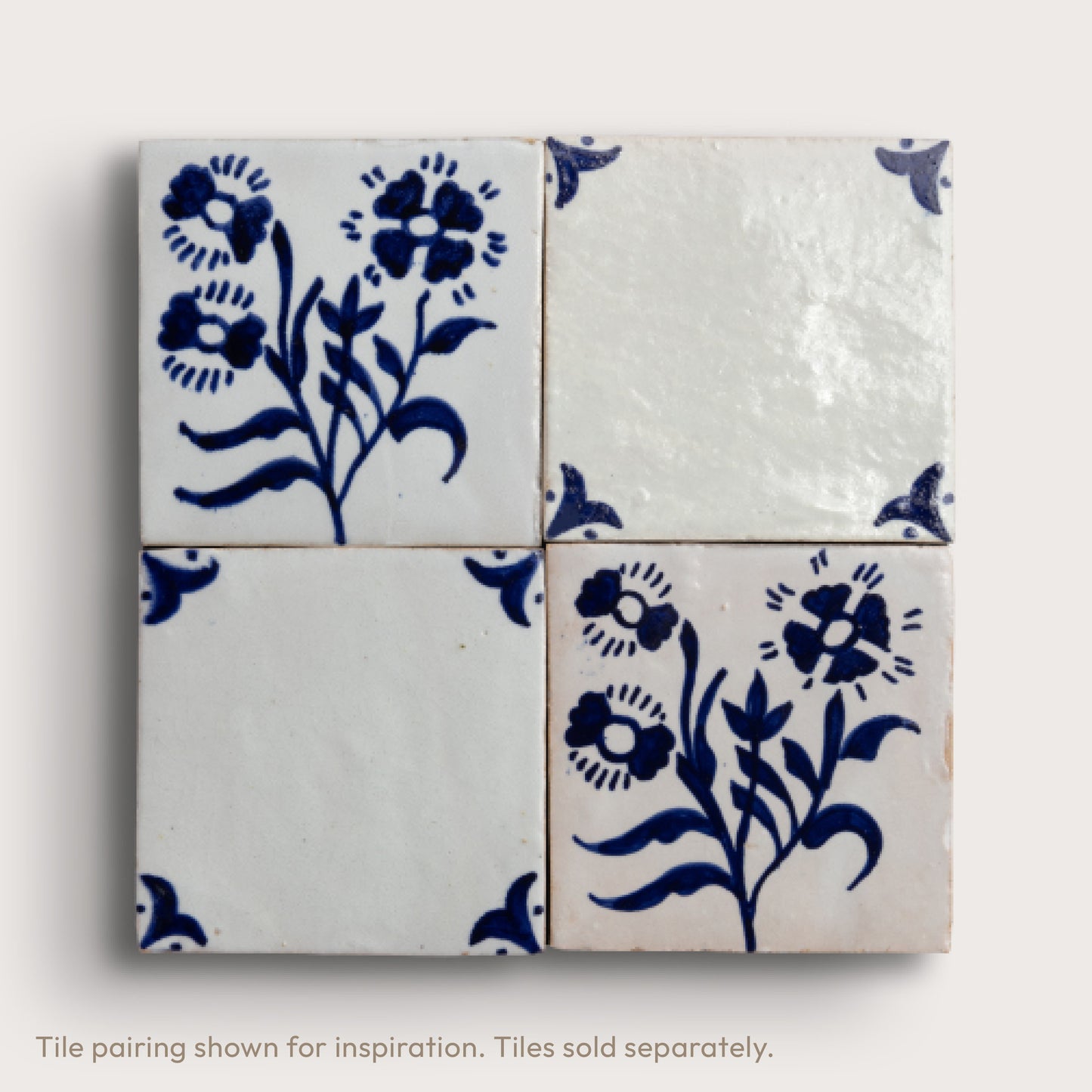 Four square zellige tiles arranged in a 2x2 grid, featuring a hand-painted blue floral pattern on a glossy white glaze, set against a light beige background.