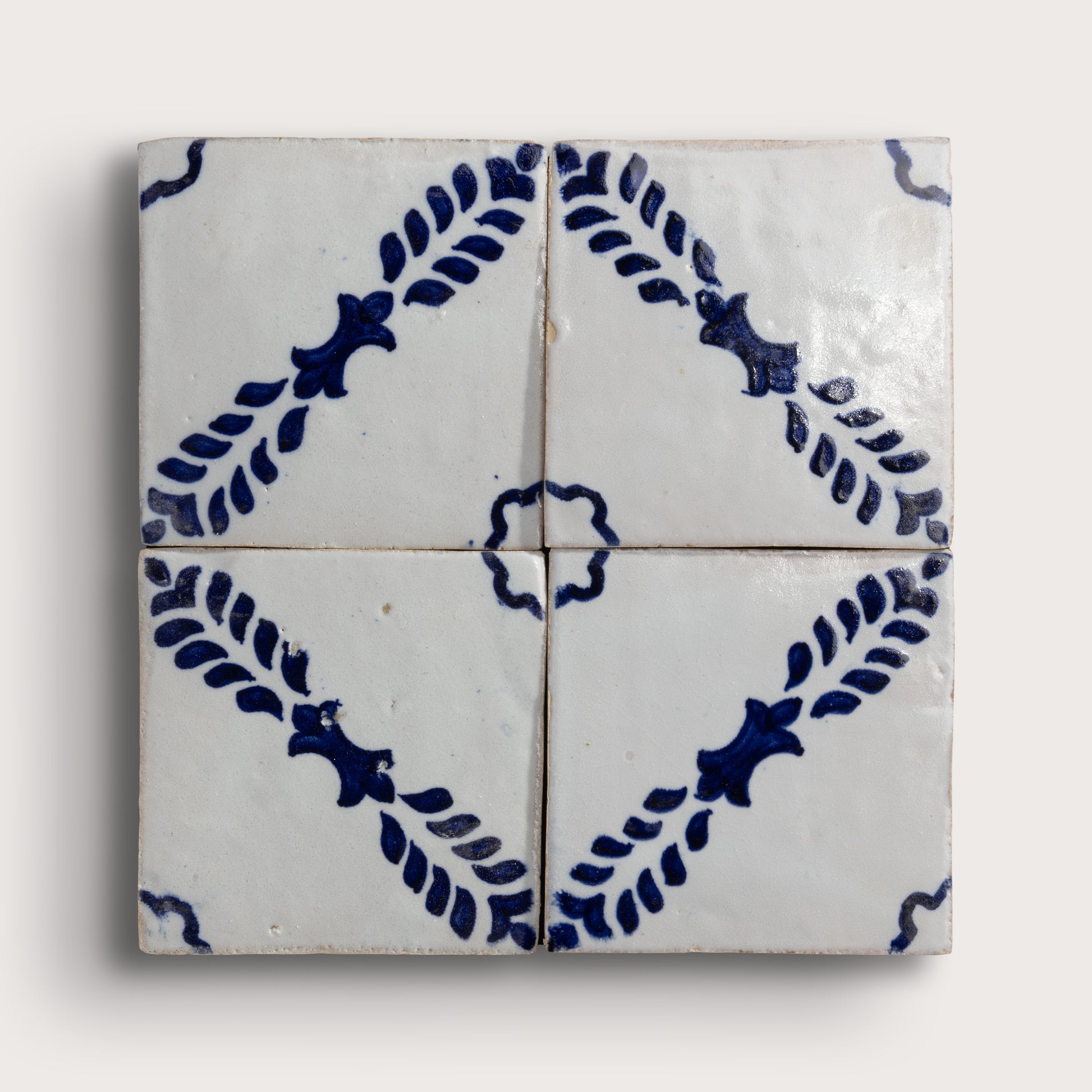 Four square zellige tiles arranged in a 2x2 grid, featuring a classic Dutch blue-and-white pattern with leafy motifs and a central rosette on a light beige background.