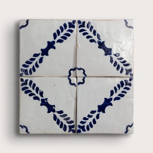 Four square zellige tiles arranged in a 2x2 grid, featuring a classic Dutch blue-and-white pattern with leafy motifs and a central rosette on a light beige background.