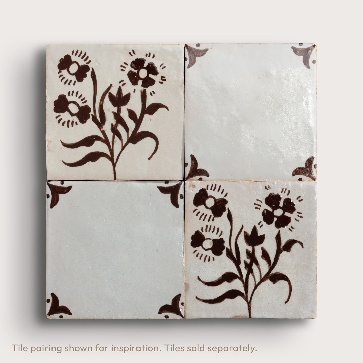 Four square zellige tiles arranged in a 2x2 grid, featuring a hand-painted dark brown floral motif on an off-white background, with two blank tiles and two decorated corner tiles.
