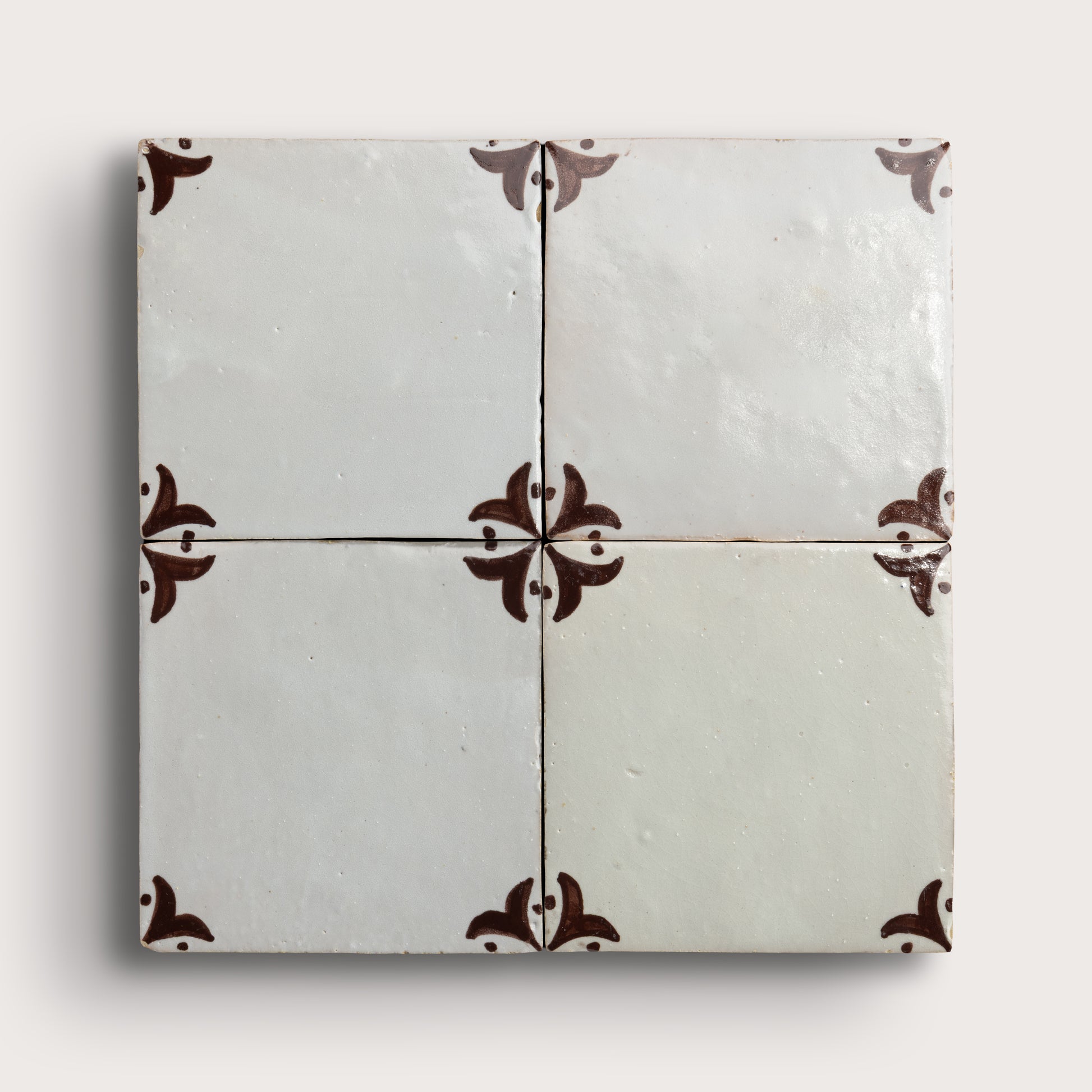 square zellige tile in a grid format with brown handpainted fleur pattern.