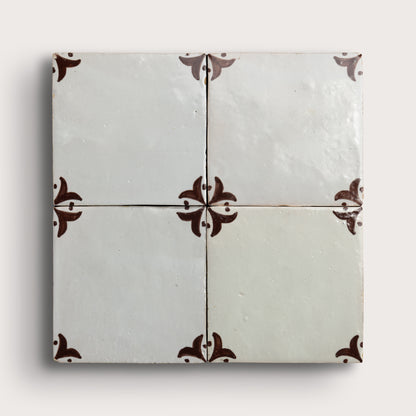 square zellige tile in a grid format with brown handpainted fleur pattern.